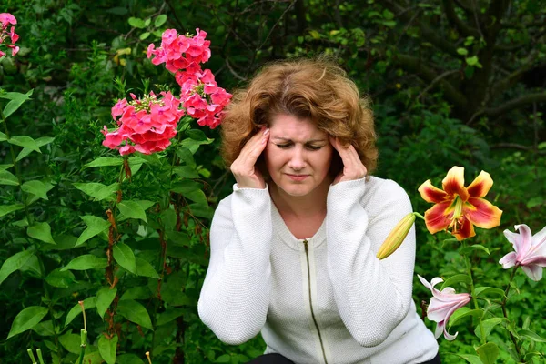 花の背景に頭痛を持つ女性 — ストック写真