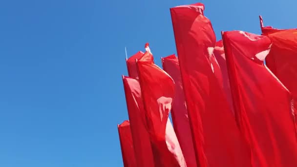 Muchas banderas rojas balanceándose en el viento contra el cielo azul — Vídeos de Stock