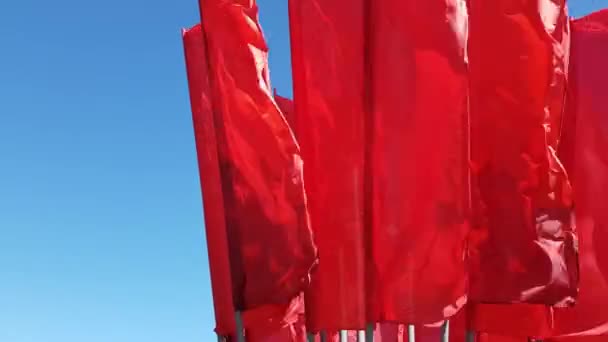 Mnoho červené vlajky, vlnící se ve větru proti modré obloze — Stock video