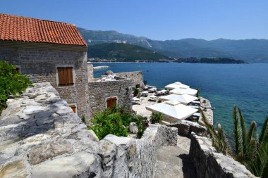Budva, Karadağ - 13 Haziran 2019. Old Town 'da denizin arka planında bir kafe olan manzara.