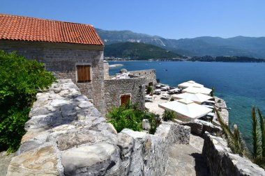 Budva, Karadağ - 13 Haziran 2019. Old Town 'da denizin arka planında bir kafe olan manzara.