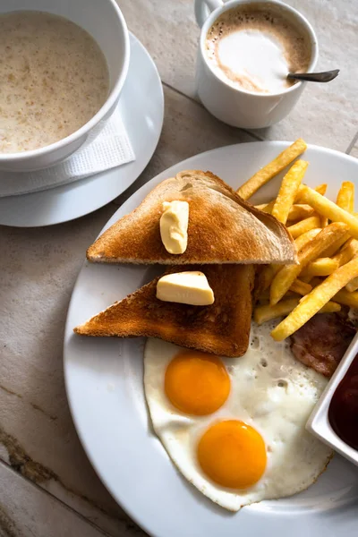 Смажені яйця з тостами та картоплею фрі на сніданок — стокове фото