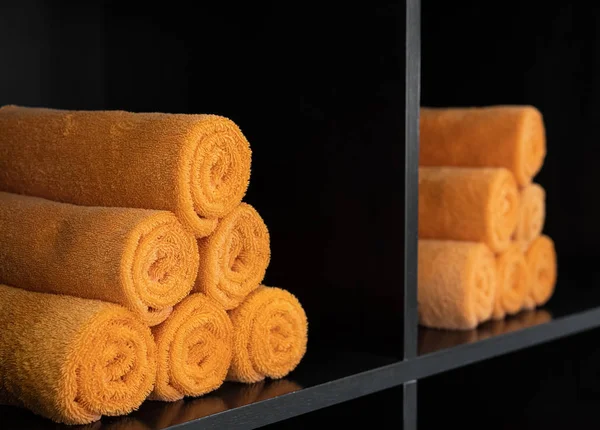 Lots of orange rolled towels on the shelves