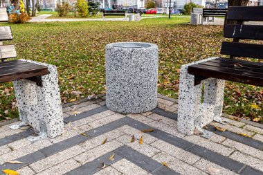 Çöp tenekesi ahşap bankın yanında.
