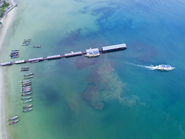 Luftaufnahme: Strand, Seebrücke und Boote am wunderschönen tropischen Meer aus der Vogelperspektive Stockbild