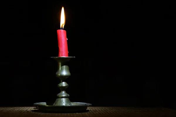 Bruciando vecchia candela vintage bronzo candeliere su sfondo di legno nero . — Foto Stock