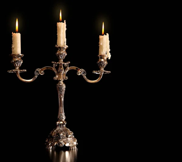 Burning old candle vintage bronze Silver candlestick. Isolated Black Background. — Stock Photo, Image