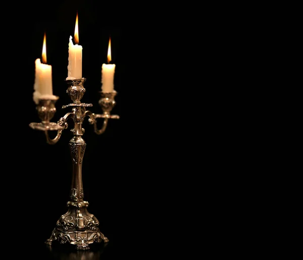 Burning old candle vintage Silver bronze candlestick. Isolated Black Background. — Stock Photo, Image