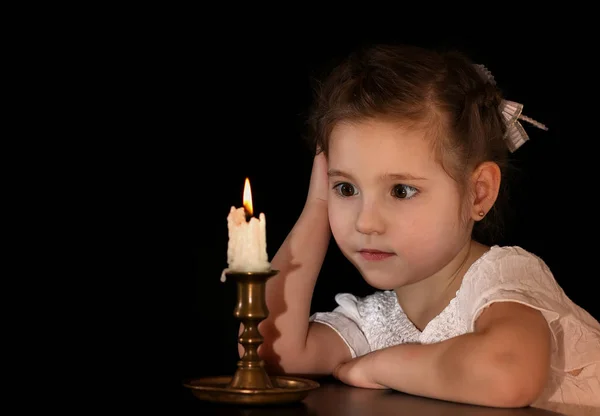 Portret dziewczyny 4-5-6 lat, patrząc na świecę na białym na czarnym tle. — Zdjęcie stockowe