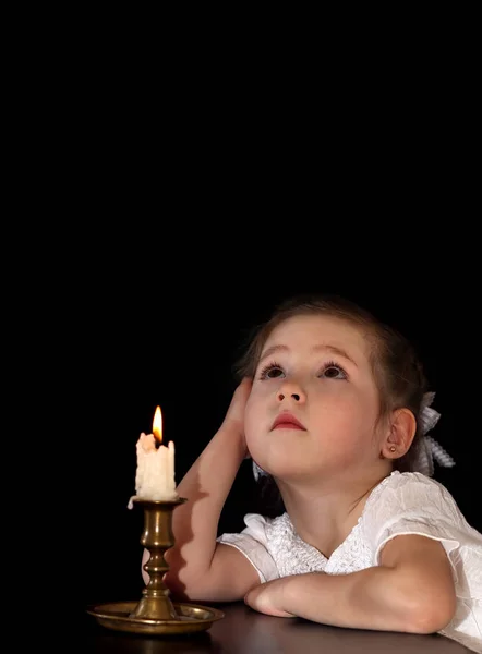 Portret van een meisje 4-5-6 jaar, kijken naar de brandende kaars geïsoleerd op zwarte achtergrond. — Stockfoto