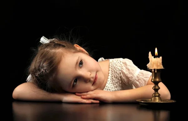 Retrato de uma menina 4-5-6 anos, olhando para a vela acesa isolada no fundo preto . — Fotografia de Stock