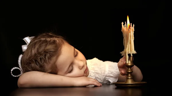 Portret van een meisje 4-5-6 jaar, kijken naar de brandende kaars geïsoleerd op zwarte achtergrond. — Stockfoto