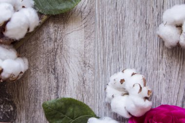 Gri bir ahşap zemin üzerine beyaz bir çerçeve pamuk çiçekler süslüyor