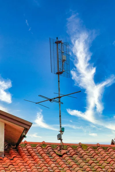 Antena tv na szczycie pomarańczowy dach przed błękitnym niebem — Zdjęcie stockowe
