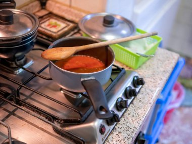İçinde ragu sosu olan bir tencere ve tahta bir kaşık.