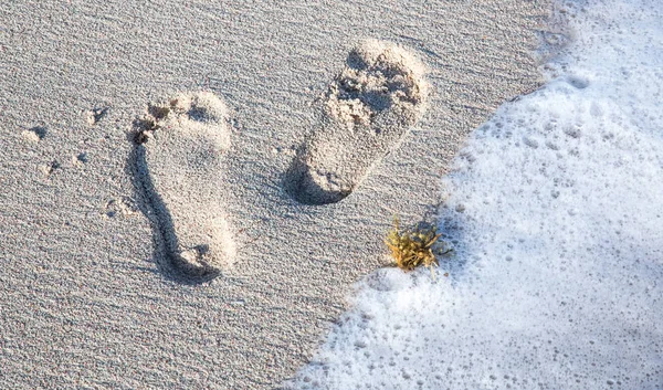 Fußabdrücke und Meerwasser an einem Sandstrand — Stockfoto