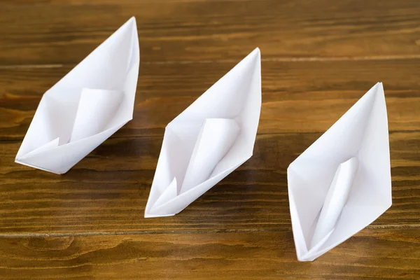 Tre papper båtar på ett träbord — Stockfoto