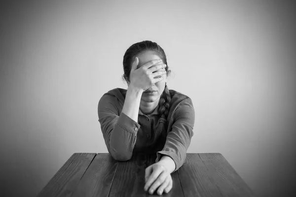 Mulher deprimida sentada a uma mesa — Fotografia de Stock