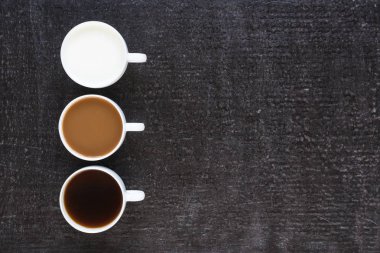 Üç bardak kahve ve siyah arka plan üzerine süt ile