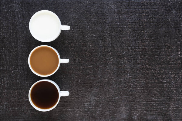 Три чашки с кофе и молоком на черном фоне
