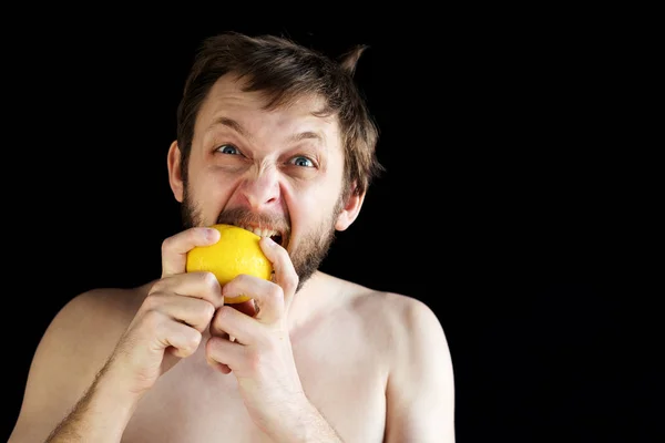 Dishevelled man eating a lemon — Stock Photo, Image