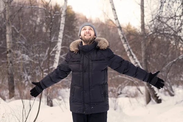 Genç adam bir kış ormandaki açık geniş kollu