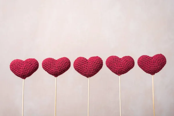 П'ять в'язаних сердець на дерев'яних паличках — стокове фото