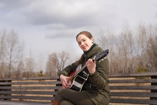 Mujer sonriente tocando la guitarra Imagen de archivo