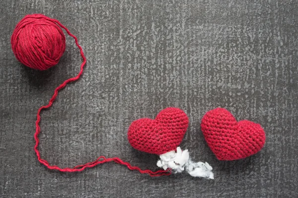 Two crocheted red hearts on a grunge board