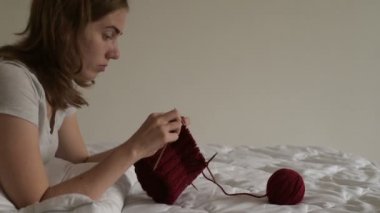 Genç kadın bir yatağa örgü