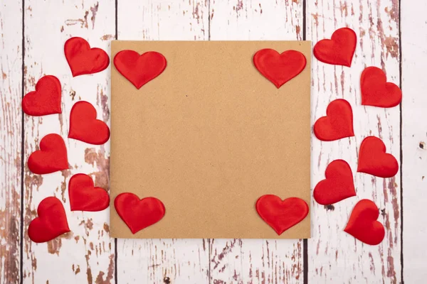 Composição plana com corações e uma folha de papel em um fundo de madeira — Fotografia de Stock
