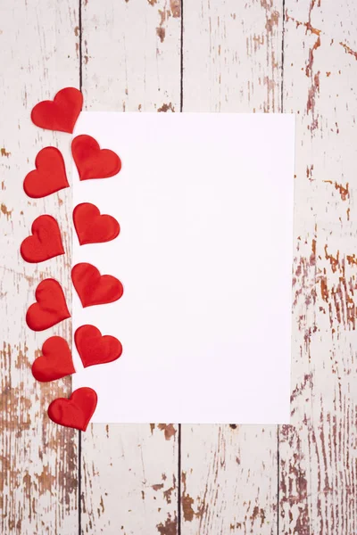 Composição plana com corações e uma folha de papel em um fundo de madeira — Fotografia de Stock