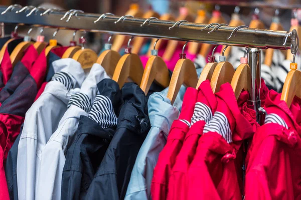 Impermeables brillantes colgando en una tienda de moda —  Fotos de Stock