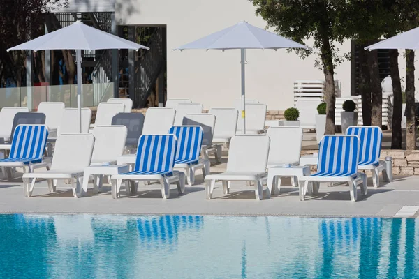 Liegestühle und Sonnenschirme am Pool — Stockfoto