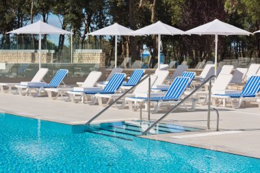 şezlong ve şemsiyeler havuz kenarında 