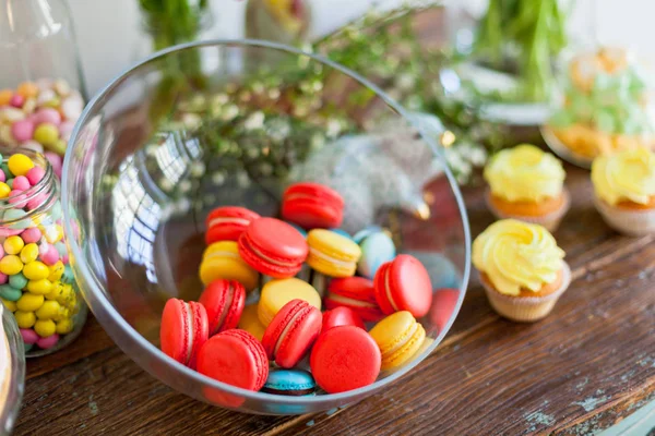 Macaroons e cupcakes na mesa de madeira — Fotografia de Stock