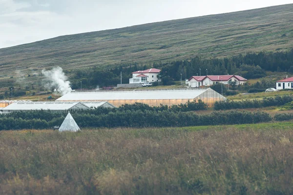 Geothermische kassen en huizen op de groene heuvels — Stockfoto