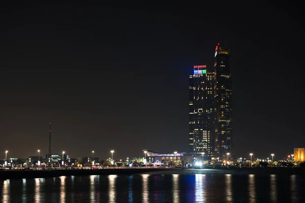 Здания Абу-Даби возвышаются над морем ночью — стоковое фото