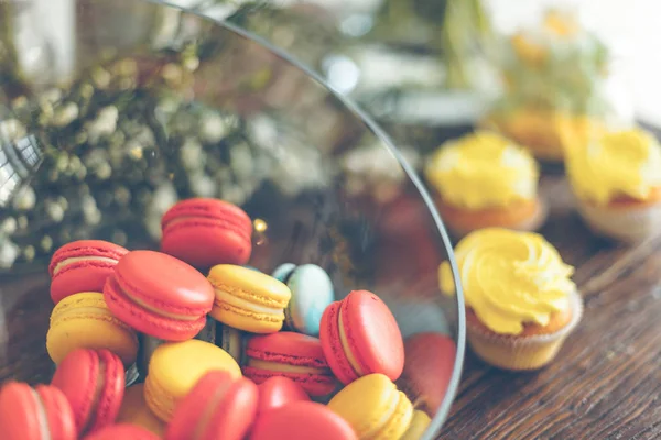 Leuchtende Makronen und Cupcakes auf einem Tisch — Stockfoto