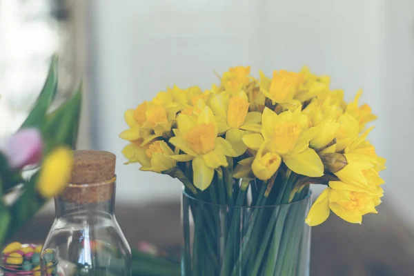 Ramo de narcisos amarillos en un jarrón de vidrio — Foto de Stock