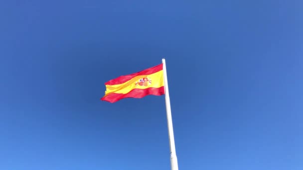 Bandera de España ondeando en el viento sobre el fondo azul claro del cielo — Vídeo de stock