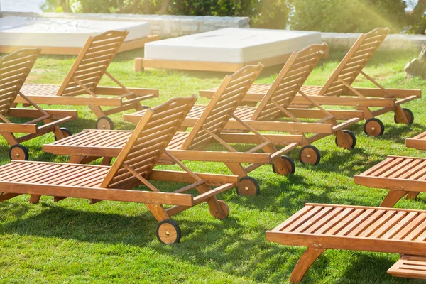 Chaises d'hôtel au bord de la piscine sur une prairie verte — Photo