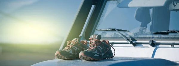 Los zapatos de trekking se están secando en un capó de coche 4wd sucio —  Fotos de Stock