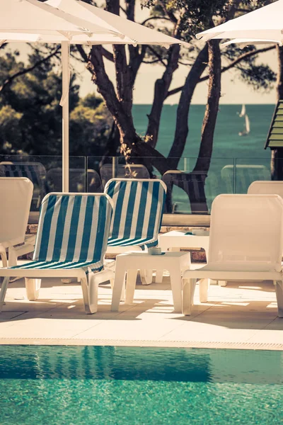 Sunbeds and umbrellas by the swimming pool on a sunny day — Stock Photo, Image