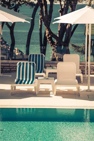 Lettini e ombrelloni in piscina in una giornata di sole — Foto Stock
