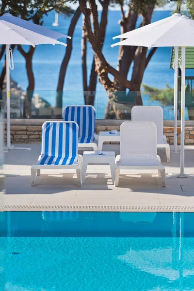 Ligbedden en parasols bij het zwembad op een zonnige dag — Stockfoto