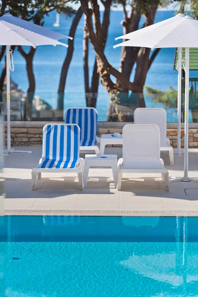 Lettini e ombrelloni in piscina in una giornata di sole — Foto Stock