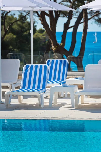 Lettini e ombrelloni in piscina in una giornata di sole — Foto Stock