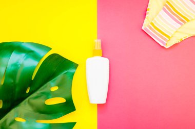 Tropikal orman palm monstera bırakır, güneş gözlüğü, güneş kremi boş şişe mockup ve kadının mayo üst parlak renk kağıt arka plan üzerinde. Metin için yaratıcı düz yatıyordu kavramı şablon yaz tatil