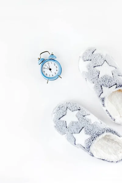 Zapatillas suaves y esponjosas y reloj despertador azul — Foto de Stock